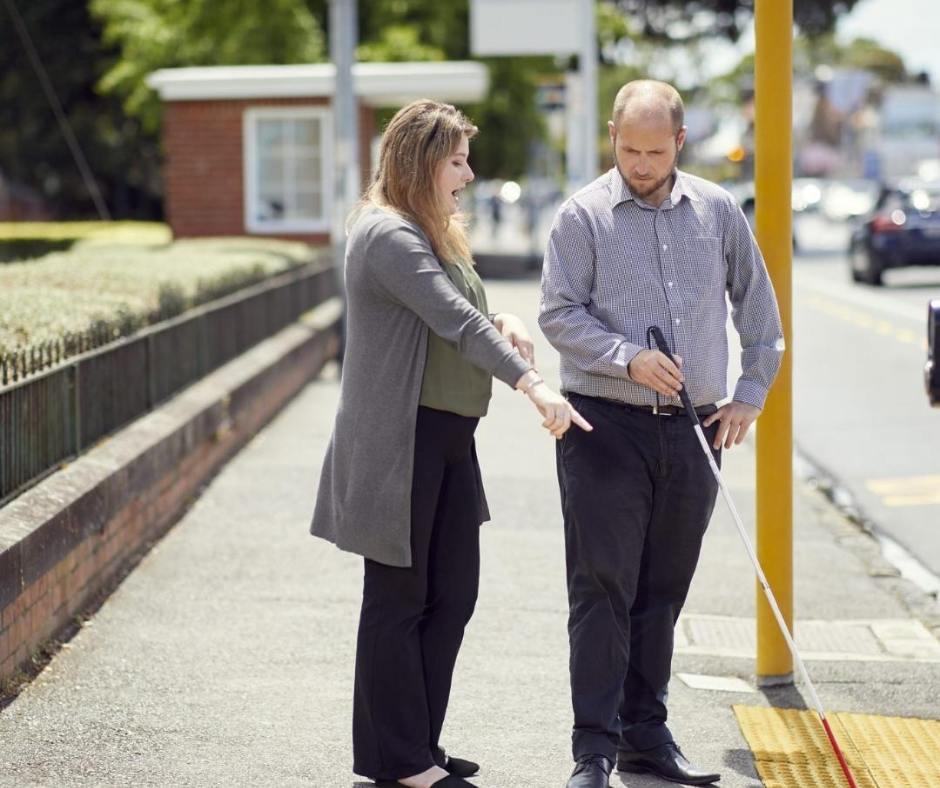 Dan Shepherd, a Blind Low Vision NZ client, learning mobility skills with his white cane. He is standing on the street with a Mobility specialist. Dan Shepherd, a Blind Low Vision NZ client, learning mobility skills with his white cane. He is standing on the street with a Mobility specialist.