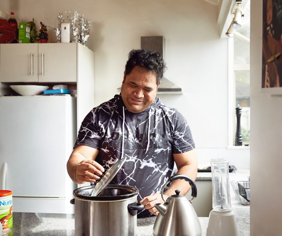 A man with low vision standing in his kitchen, cooking happily. A man with low vision standing in his kitchen, cooking happily.