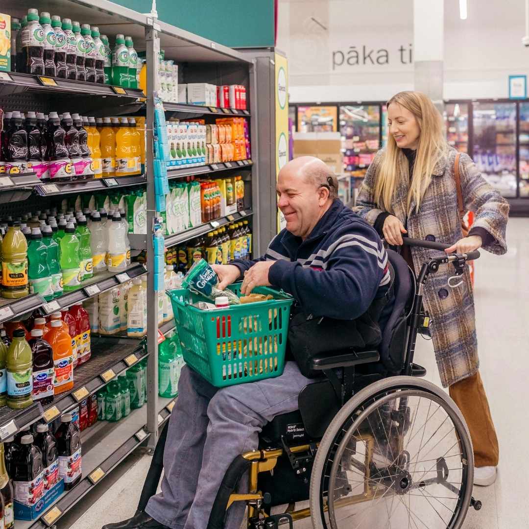 A man in a wheelchair and his carer shopping in a supermarket. A man in a wheelchair and his carer shopping in a supermarket.