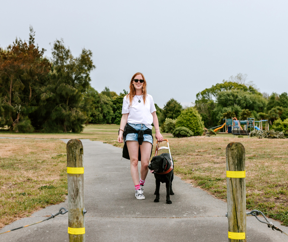 Laura and her guide dog Ryder walking through a park. Laura and her guide dog Ryder walking through a park.