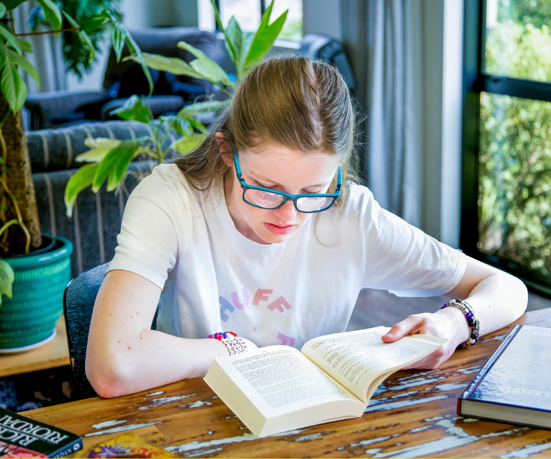 Asha reading a book at her dining table.